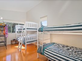 A bedroom with bunk beds and a shelf at The Old Barn in Whitianga