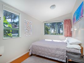 A bedroom with a bed, windows, fish poster and light fixture at The Old Barn in Whitianga