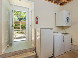 A laundry room with appliances and an open door at The Old Barn in Whitianga