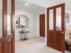 An entryway with a mirror and flowers on a table at Nukuhau Bliss - Taupo Holiday Home, Taupo Central