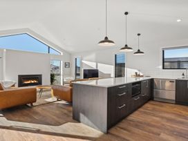 A living room with a fireplace and kitchen island at Harper on Hadley - Cromwell Holiday Home, Cromwell