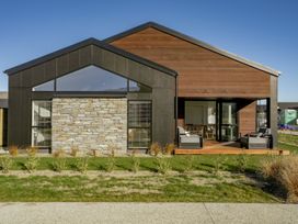 A house with a stone wall and large windows at Harper on Hadley - Cromwell Holiday Home in Cromwell
