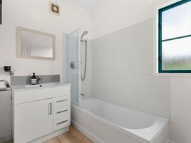 A bathroom with a shower, bath, sink, and mirror at Waipu in Waipu