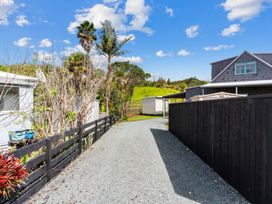 A gravel driveway with a fence and houses at Waipu in Waipu