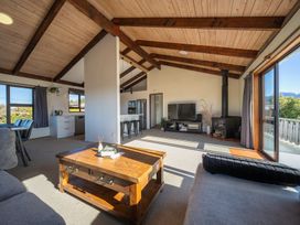 A living room with a sofa, coffee table, and television at Four Peaks on Matai - Te Anau