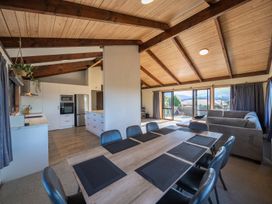 A living room with a dining table and kitchen area at Four Peaks on Matai - Te Anau