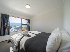 A bedroom with a bed and window view at Four Peaks on Matai - Te Anau Holiday Home