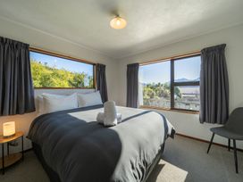 A bedroom with a bed and windows at Four Peaks on Matai - Te Anau Holiday Home Te Anau