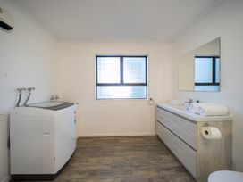 A bathroom with a washing machine and sink at Four Peaks on Matai - Te Anau Holiday Home