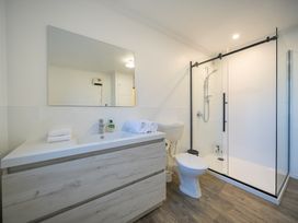 A bathroom with a shower and vanity at Four Peaks on Matai - Te Anau Holiday Home