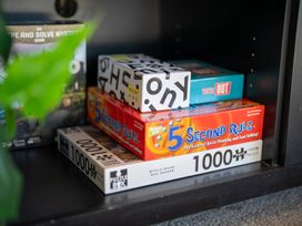 A shelf with board games including 5 Second Rule and 1000 Piece Puzzle at Four Peaks on Matai - Te Anau Holiday Home in Te Anau