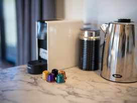 A coffee machine and kettle with coffee pods on a counter at Four Peaks on Matai - Te Anau Holiday Home
