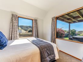 A bedroom with a bed and windows at Picton Holiday Home