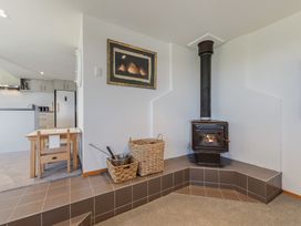A living room with a wood stove and small table at Picton Holiday Home