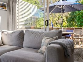 A living room with a sofa and view of outdoor seating area at White-Sands Hideaway - Waihi Beach