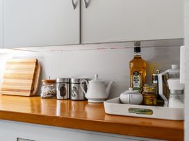A countertop with cutting board, tea pot, oil bottle, canisters, and jars at White-Sands Hideaway - Waihi Beach
