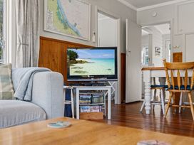 A living room with a television and furniture at White-Sands Hideaway - Waihi Beach