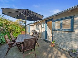 An outdoor dining area with a table and chairs at White-Sands Hideaway - Waihi Beach