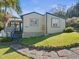 A house with a lawn and pathway at White-Sands Hideaway - Waihi Beach