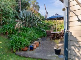 A garden with a table and chairs under an umbrella at White-Sands Hideaway - Waihi Beach