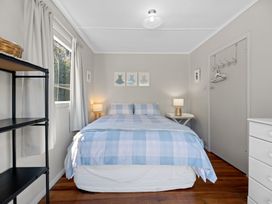 A bedroom with a bed and lamp at White-Sands Hideaway - Waihi Beach