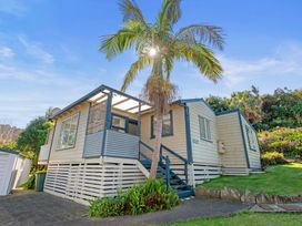 A house with a deck and palm tree at White-Sands Hideaway - Waihi Beach