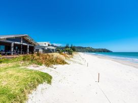 A beach with a house and deck at White-Sands Hideaway - Waihi Beach