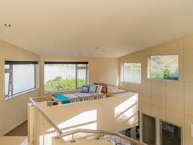 A living room with a bed and large windows at Bay View Escape - Whitianga Holiday Home Whitianga