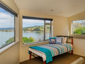 A bedroom with a bed and a view of the water at Bay View Escape - Whitianga Holiday Home, Whitianga