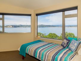 A bedroom with a bed by windows at Bay View Escape - Whitianga
