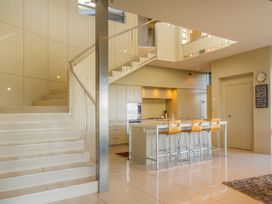 A kitchen with a staircase and bar stools at Bay View Escape - Whitianga