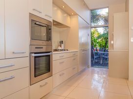 A kitchen with appliances and a window overlooking a deck at Bay View Escape - Whitianga
