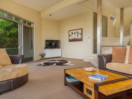 A living room with a television and staircase at Bay View Escape - Whitianga