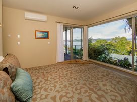 A bedroom with a bed and large window overlooking the outside at Bay View Escape - Whitianga