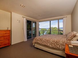 A bedroom with a bed, dresser, and window at Bay View Escape - Whitianga