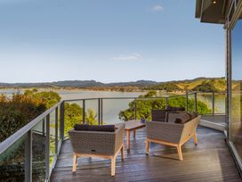 An outdoor seating area with chairs and a table overlooking a river at Bay View Escape - Whitianga Holiday Home in Whitianga