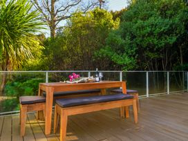 A wooden table and benches in an outdoor seating area at Bay View Escape - Whitianga