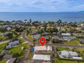 An aerial view of a coastal residential area with houses near the ocean at Whangapoua