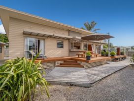 An outdoor area with a wooden deck and table at Whangapoua 