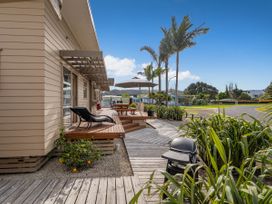 An outdoor area with a deck, table, chairs, and umbrella at Whangapoua