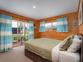 A bedroom with a bed and curtains at Whangapoua