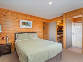 A bedroom with a bed, nightstand, lamp and sliding doors at Whangapoua