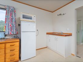 A kitchen with a refrigerator, microwave, and sink at Whangapoua