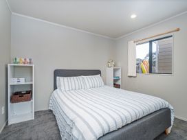 A bedroom with a bed and shelf at Whangapoua