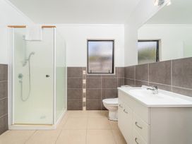 A bathroom with a shower, toilet, and sink at Whangapoua