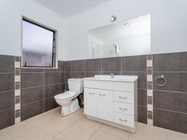 A bathroom featuring a toilet, sink, and mirror at Whangapoua