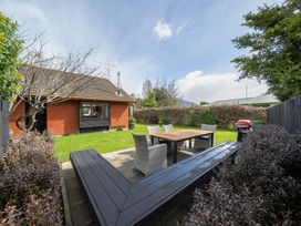 A garden with outdoor seating and a grill at Te Anau - Holiday Home