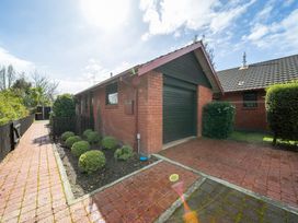 A brick house with a garage door and pathway at Te Anau - Holiday Home