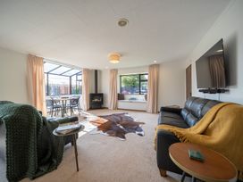 A living room with a sofa, table, chairs and a fireplace at Te Anau - Holiday Home