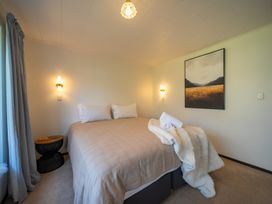 A bedroom with a bed, nightstand, and wall art at Te Anau - Holiday Home